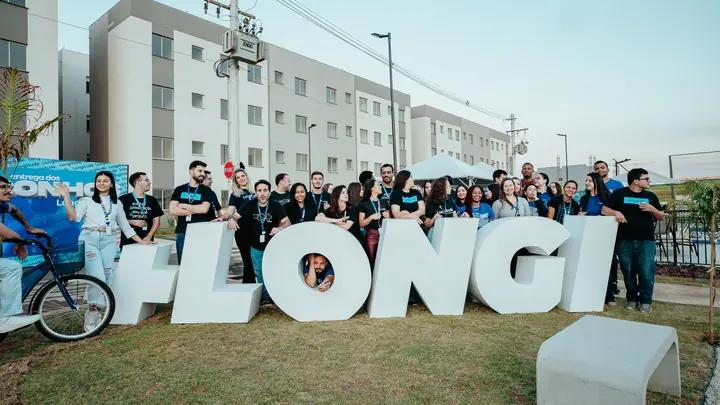 Equipe e moradores reunidos junto às letras gigantes na festa de entrega.