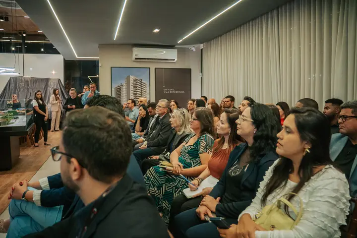 Corretores assistem à apresentação de um lançamento no stand de vendas.