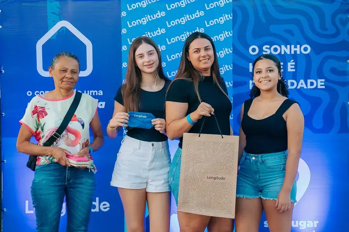 Moradoras sorriem com a sacola de boas-vindas na entrega das chaves.